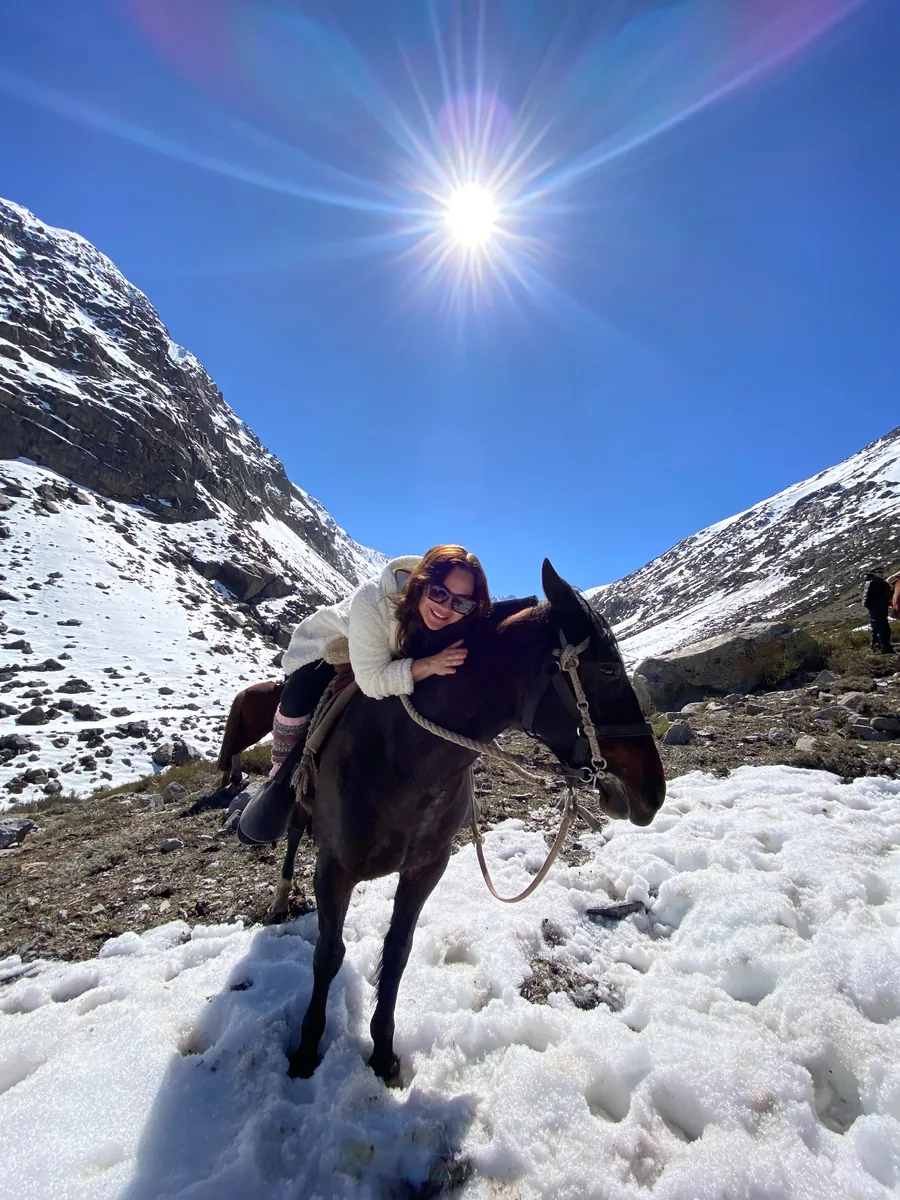 Juliana Batista com um cavalo em paisagem de montanha